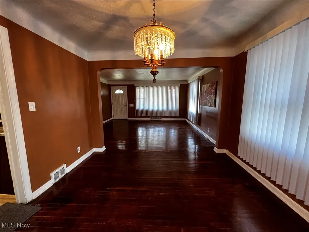Corridor with dark hardwood / wood-style floors and a chandelier