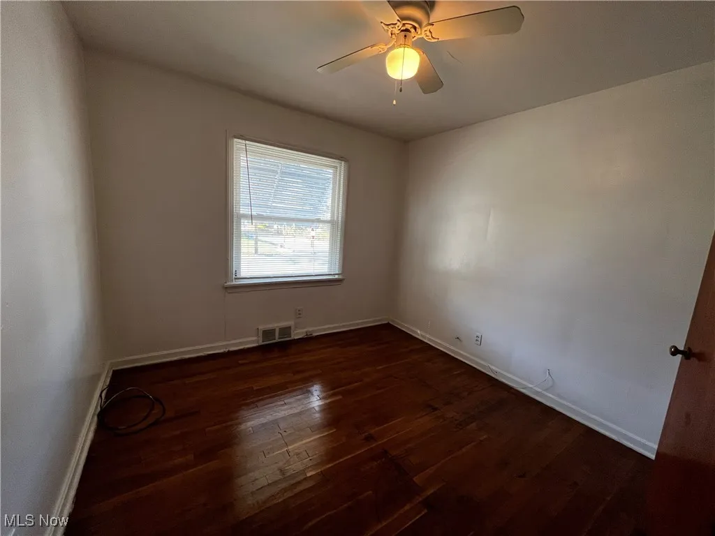 Spare room featuring ceiling fan and dark hardwood / wood-style flooring