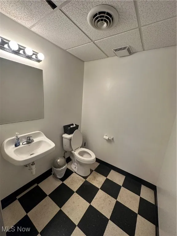 Bathroom with toilet, sink, and a drop ceiling