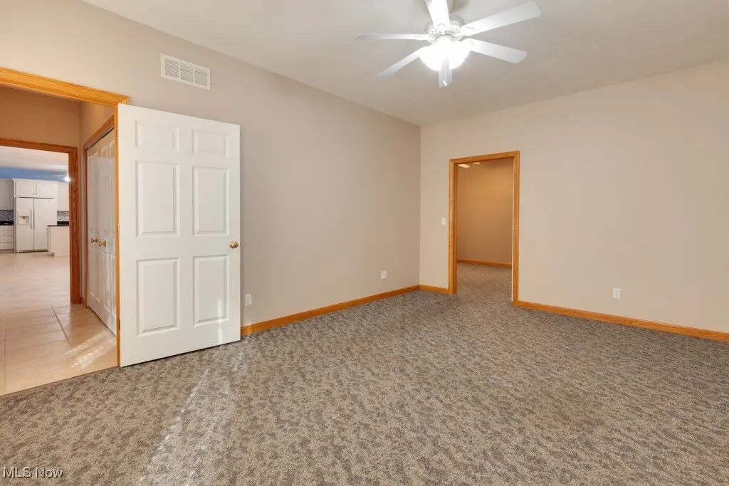 Unfurnished room featuring ceiling fan and carpet