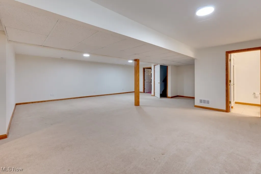 Basement featuring light carpet and a paneled ceiling