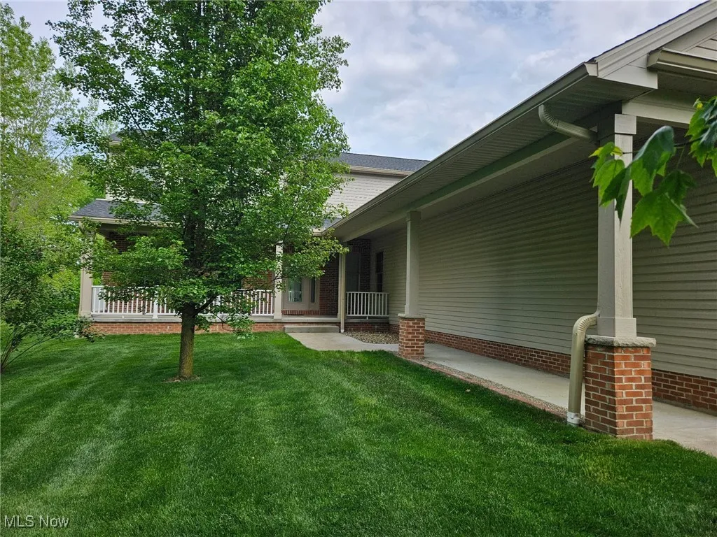 View of grassy yard with covered porch