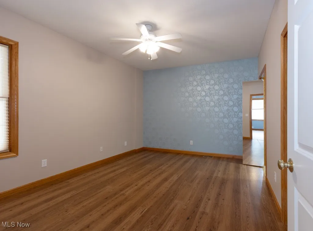 Empty room with wood-type flooring and ceiling fan