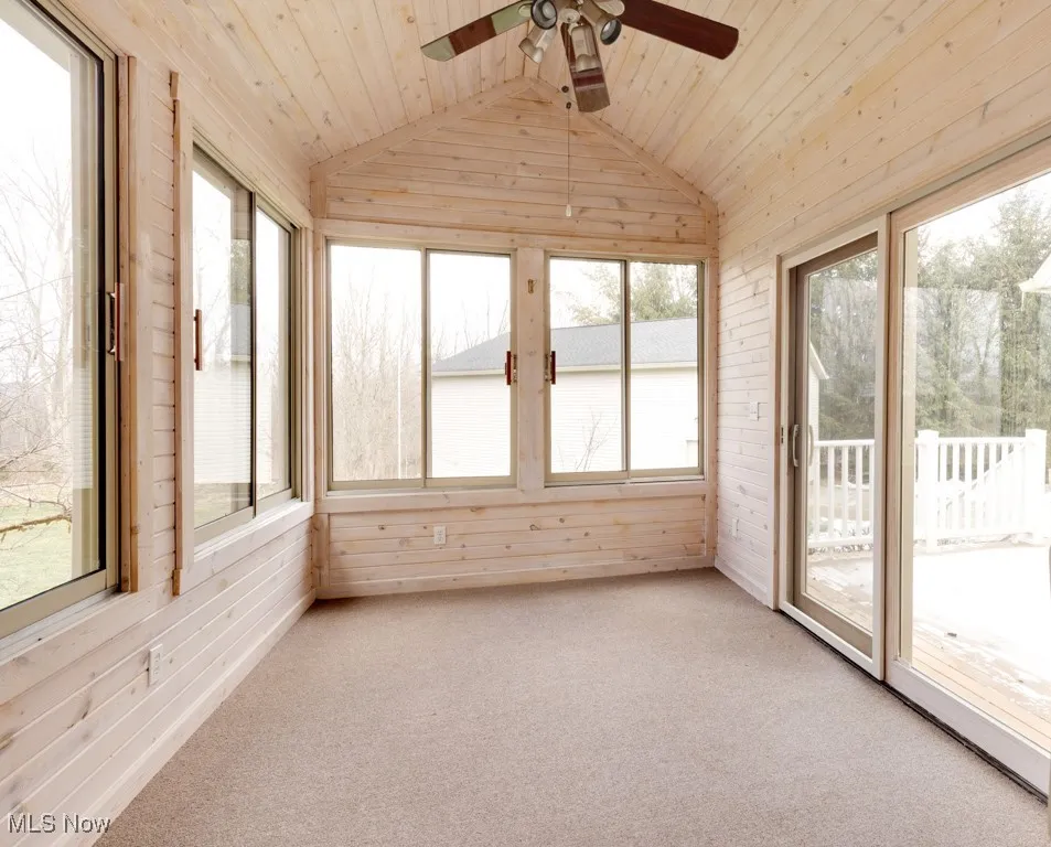 Unfurnished sunroom with ceiling fan, lofted ceiling, and wood ceiling