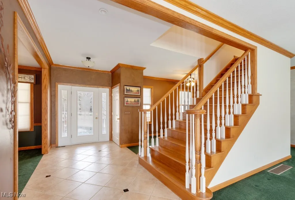 Foyer featuring ornamental molding and light tile patterned floors