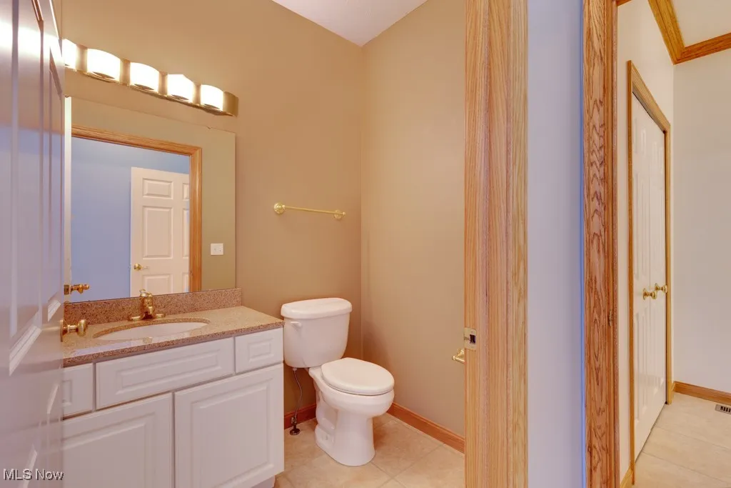 Bathroom featuring vanity, crown molding, tile patterned floors, and toilet