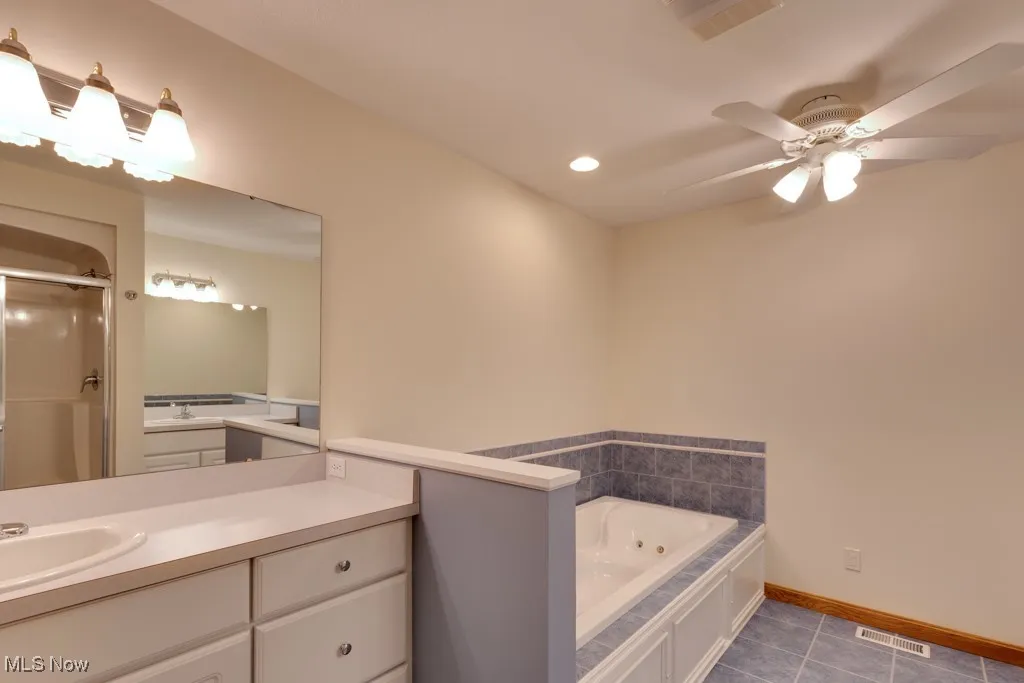Bathroom with vanity, tile patterned floors, ceiling fan, and separate shower and tub