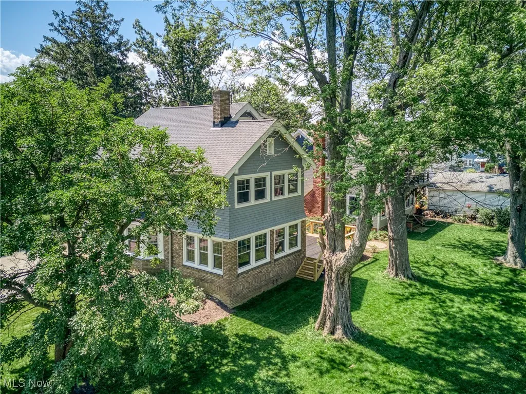 Back of property featuring a yard, a chimney, and a shingled roof