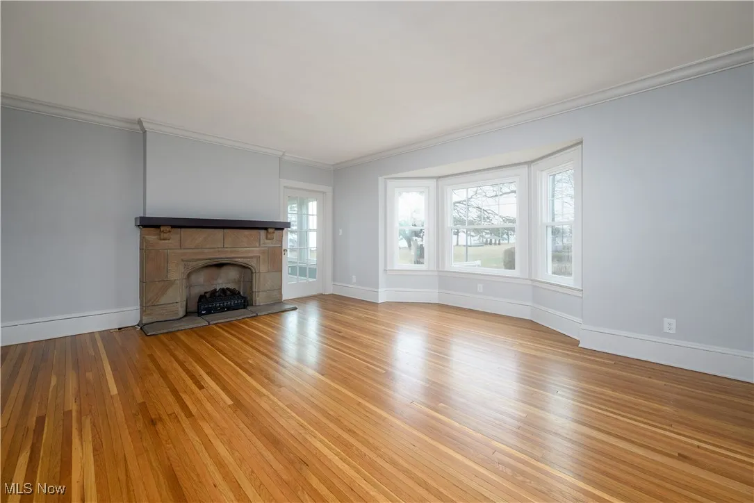 Unfurnished living room with crown molding, a tile fireplace, and light wood-type flooring
