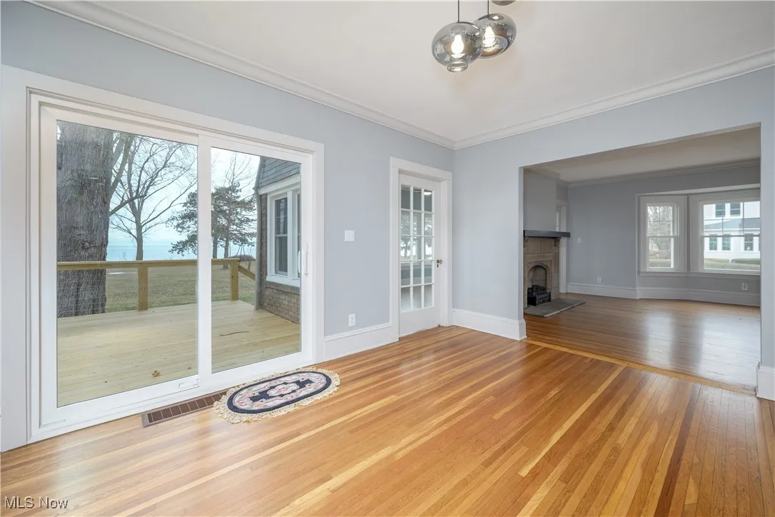 Unfurnished living room with wood-type flooring and ornamental molding