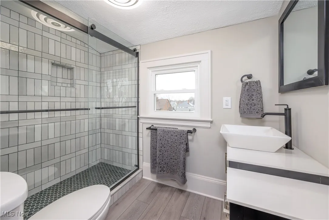 Bathroom featuring vanity, an enclosed shower, wood-type flooring, a textured ceiling, and toilet