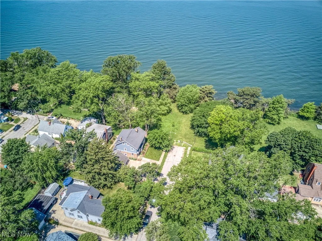 Aerial view of property and surrounding area featuring nearby suburban area and a large body of water