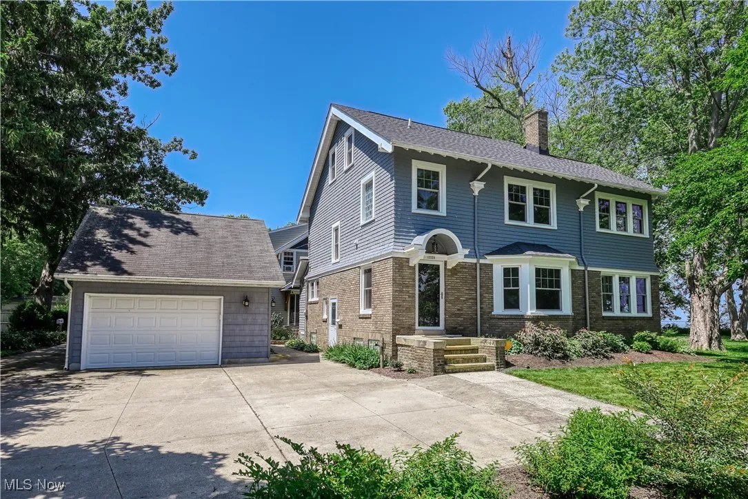 View of front of house featuring a chimney, a garage, and an outdoor structure