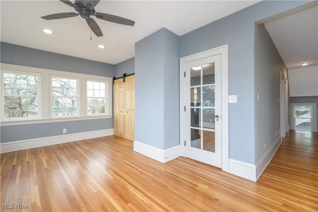 Empty room featuring light hardwood / wood-style floors, a barn door, and ceiling fan