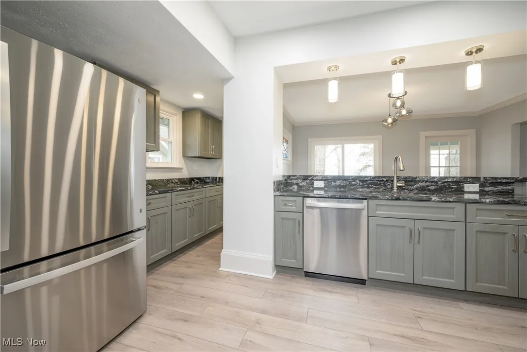 Kitchen with pendant lighting, sink, appliances with stainless steel finishes, plenty of natural light, and light hardwood / wood-style floors