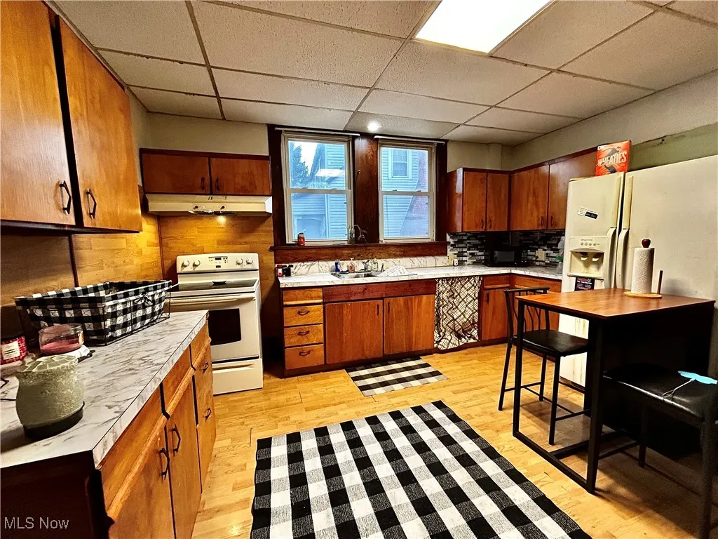 Kitchen featuring a paneled ceiling, sink, decorative backsplash, electric range, and light hardwood / wood-style flooring