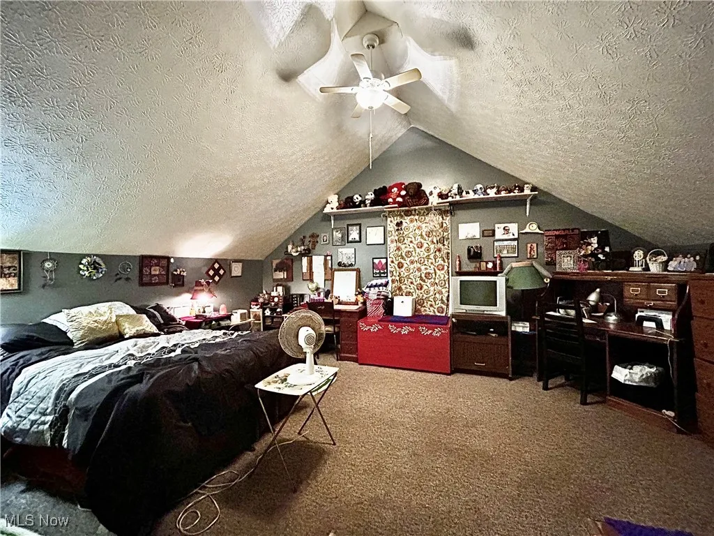 Bedroom with vaulted ceiling, carpet flooring, and a textured ceiling