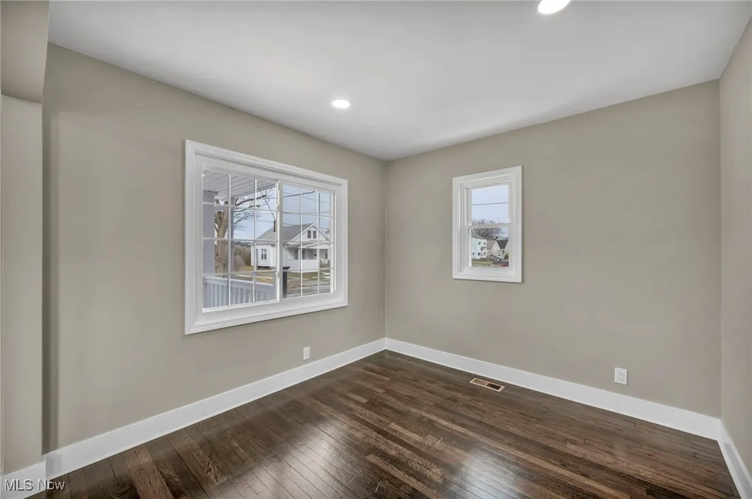 Unfurnished room with dark wood-type flooring and plenty of natural light