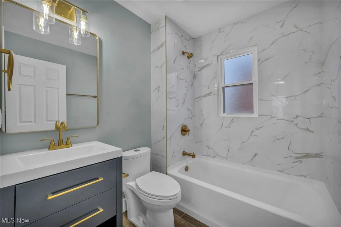 Full bathroom with tiled shower / bath, vanity, toilet, and hardwood / wood-style floors