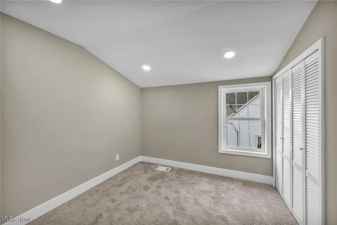 Empty room with lofted ceiling and light colored carpet