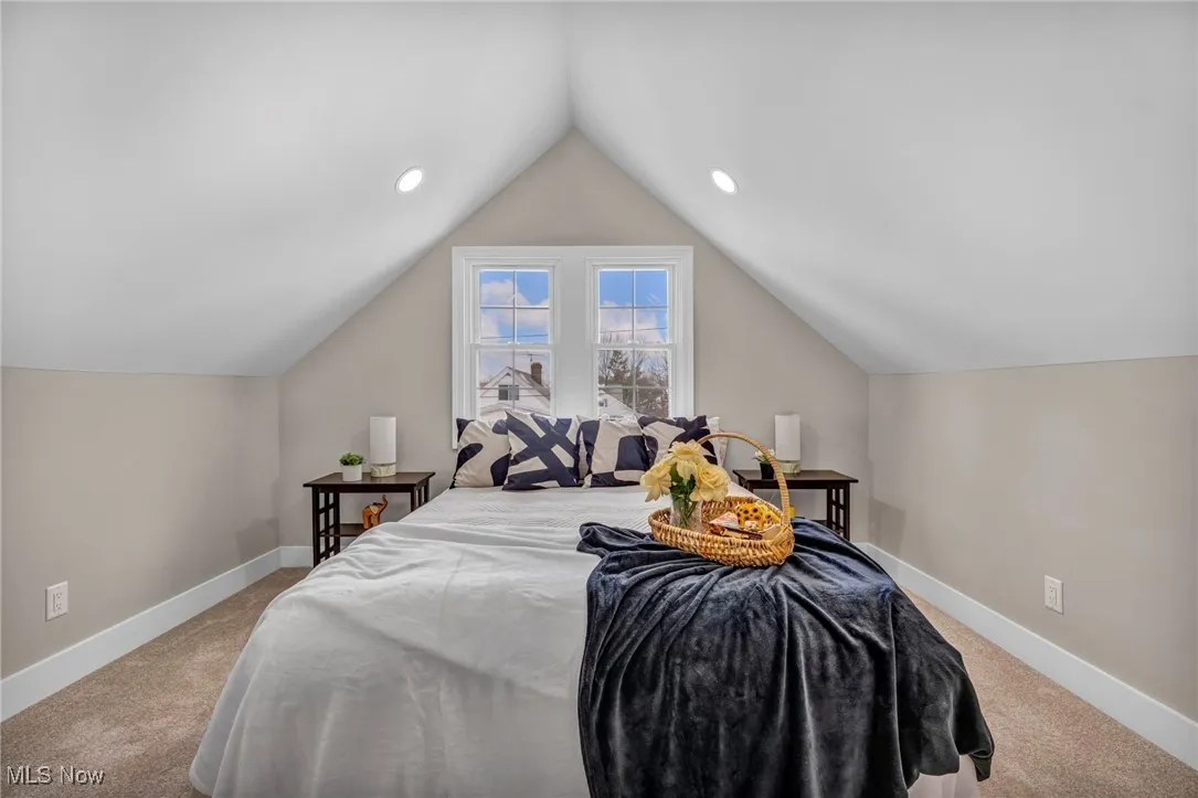 Bedroom featuring vaulted ceiling, baseboards, and carpet floors
