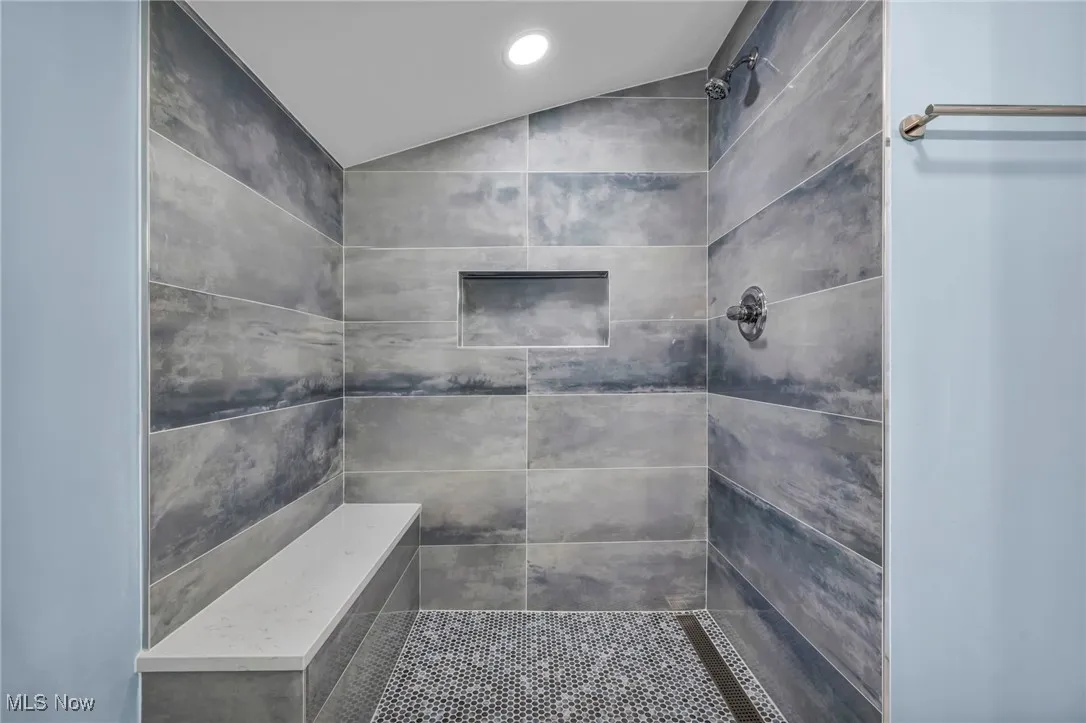 Bathroom with lofted ceiling and a tile shower