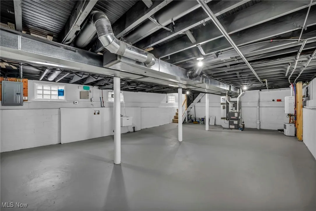 Basement with heating unit, electric panel, and water heater