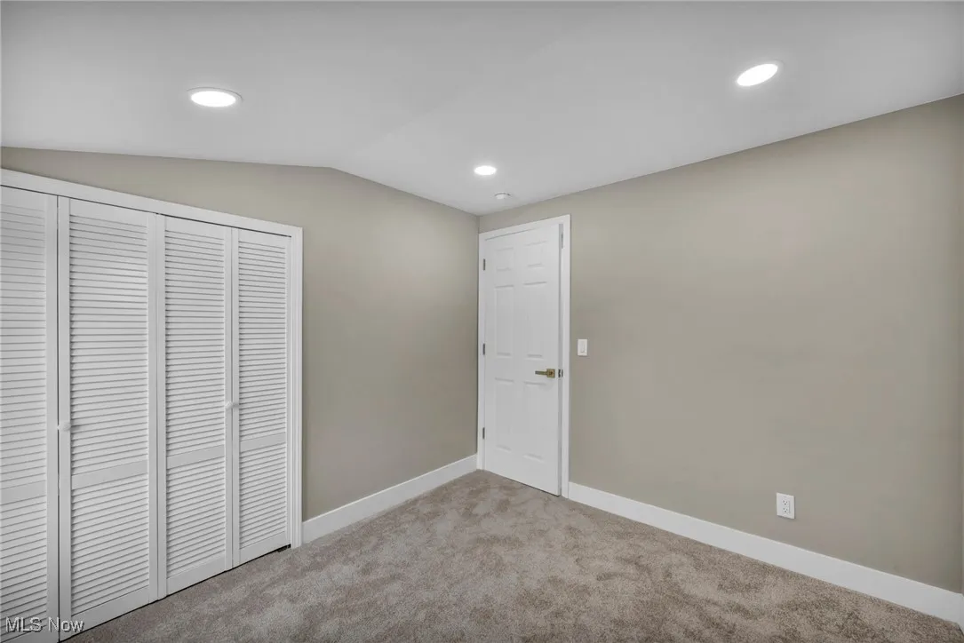 Unfurnished bedroom with vaulted ceiling, light carpet, and a closet
