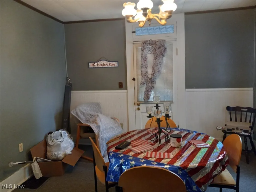 Dining space with a chandelier, carpet, and ornamental molding