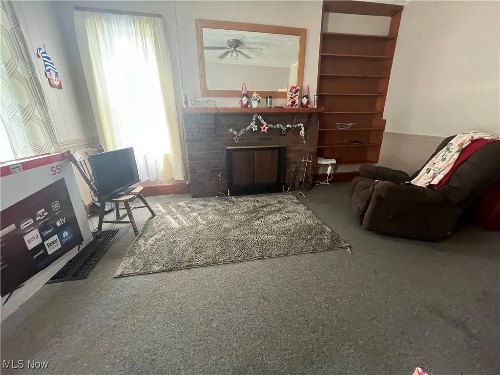 Living area featuring carpet flooring and a brick fireplace