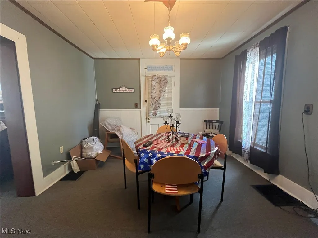 Dining room with carpet flooring, a notable chandelier, and crown molding