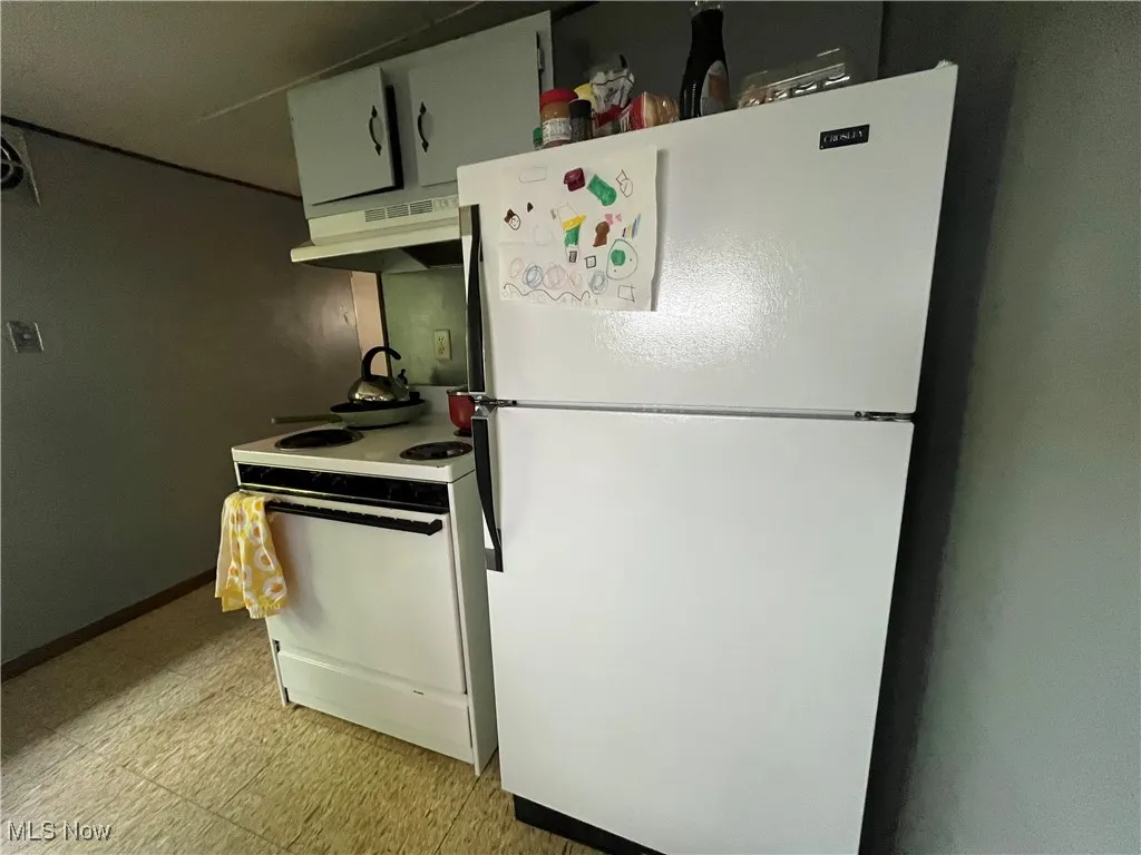 Kitchen featuring light tile patterned floors and white appliances