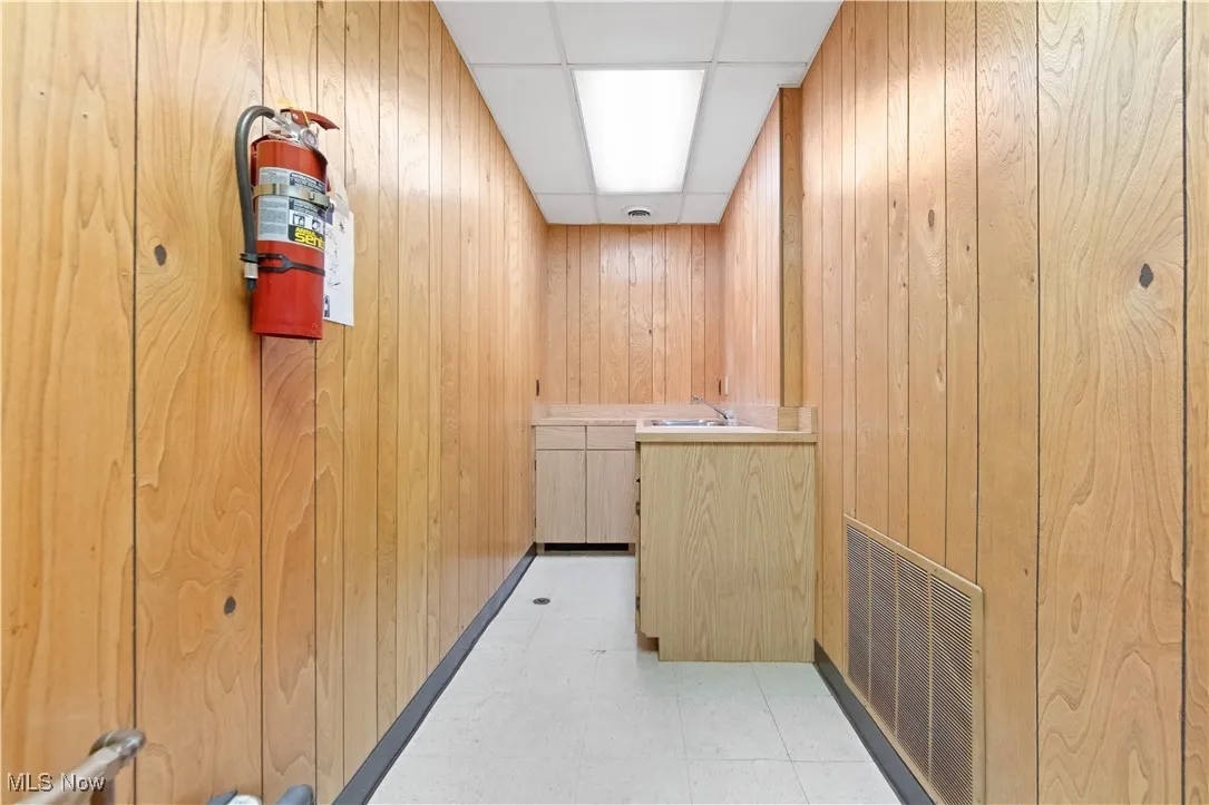 Hall with a paneled ceiling and wooden walls
