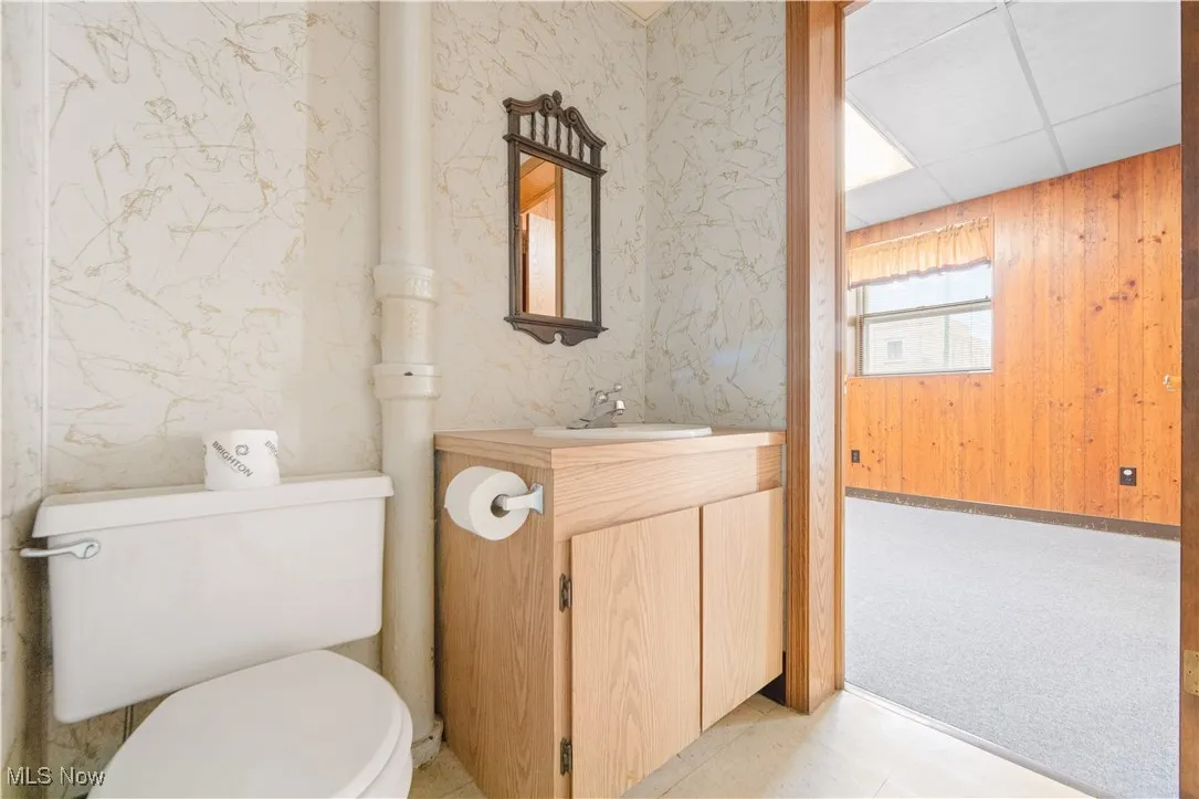 Bathroom with toilet, vanity, and a drop ceiling