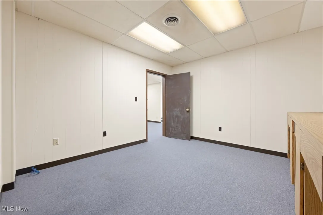 Basement featuring dark carpet and a drop ceiling