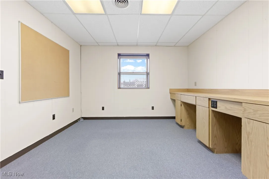 Unfurnished office with a drop ceiling and light colored carpet