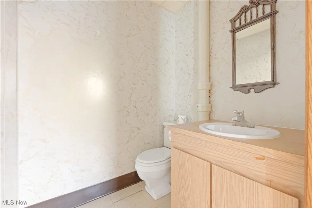 Bathroom with toilet, vanity, and tile patterned flooring