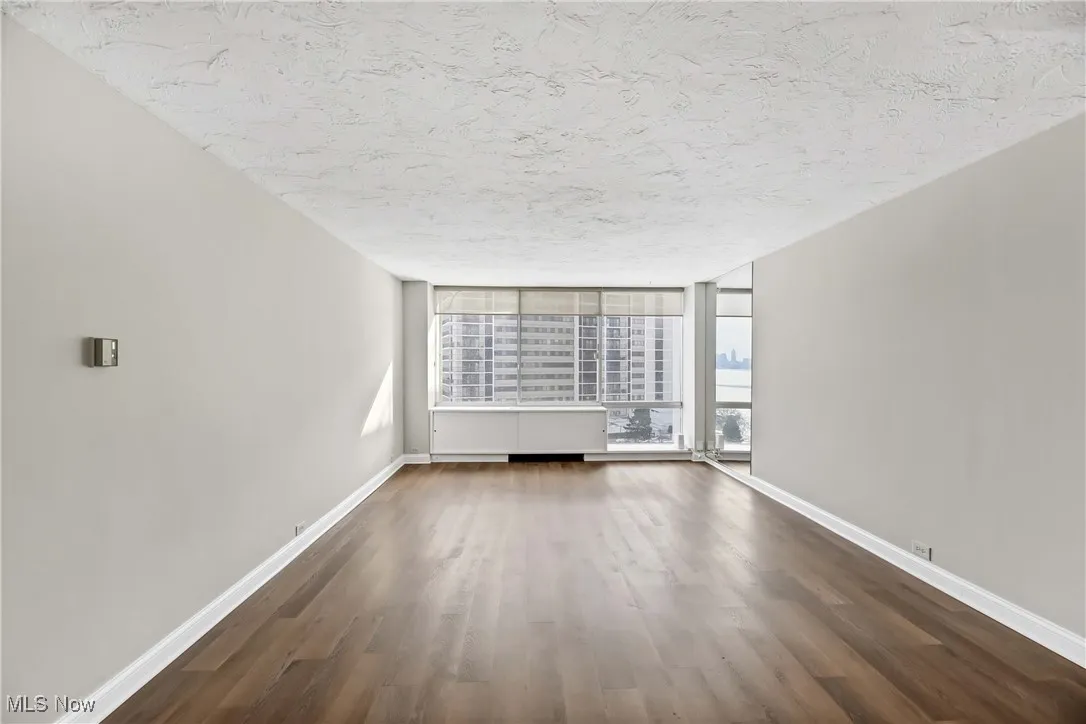 Unfurnished living room with a wall of windows, dark hardwood / wood-style flooring, and a textured ceiling