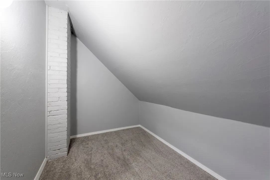 Additional living space with vaulted ceiling and carpet