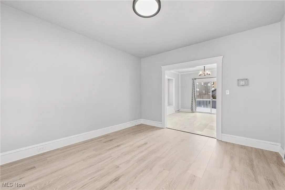 Spare room featuring light wood-type flooring and a chandelier