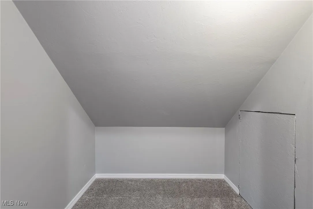 Additional living space with vaulted ceiling, carpet floors, and a textured ceiling