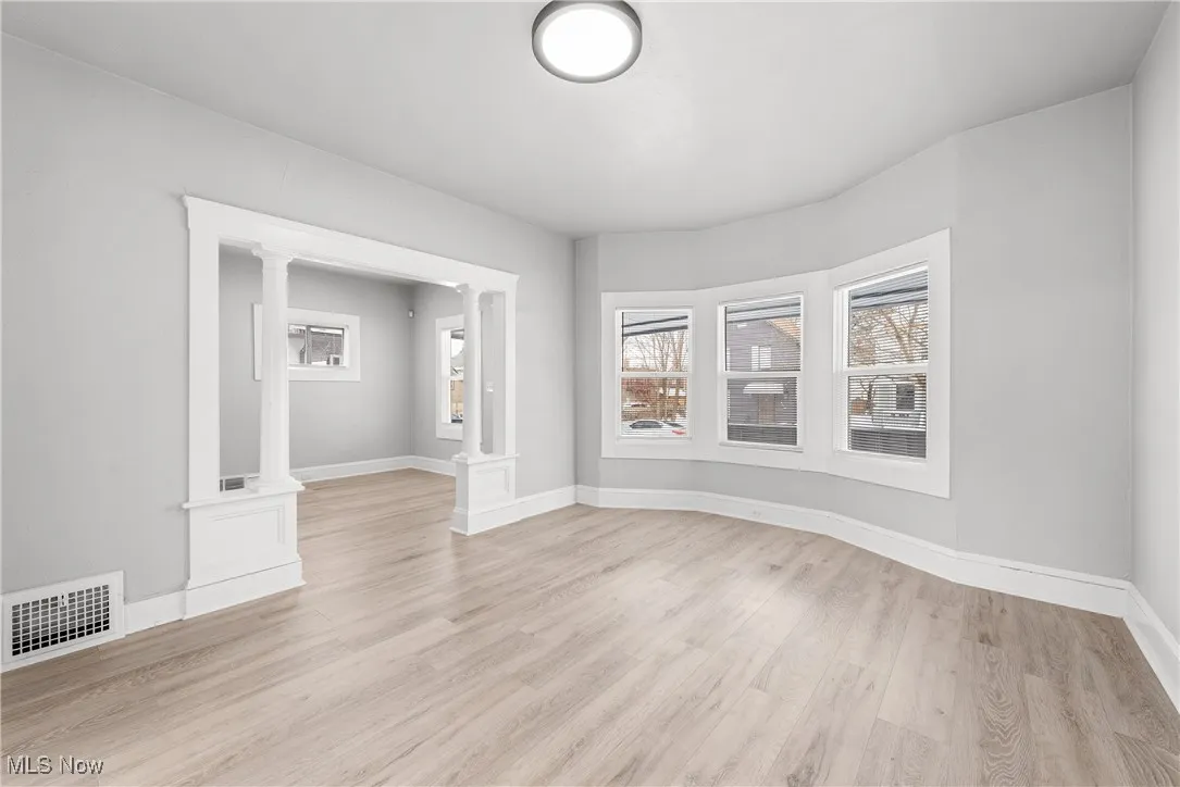 Spare room featuring light wood-type flooring and ornate columns