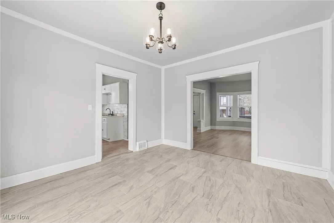 Unfurnished dining area with sink, crown molding, and a chandelier