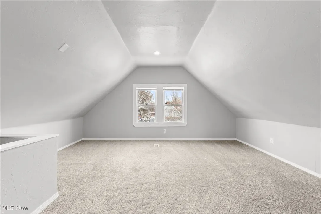 Bonus room with carpet, vaulted ceiling, and a textured ceiling