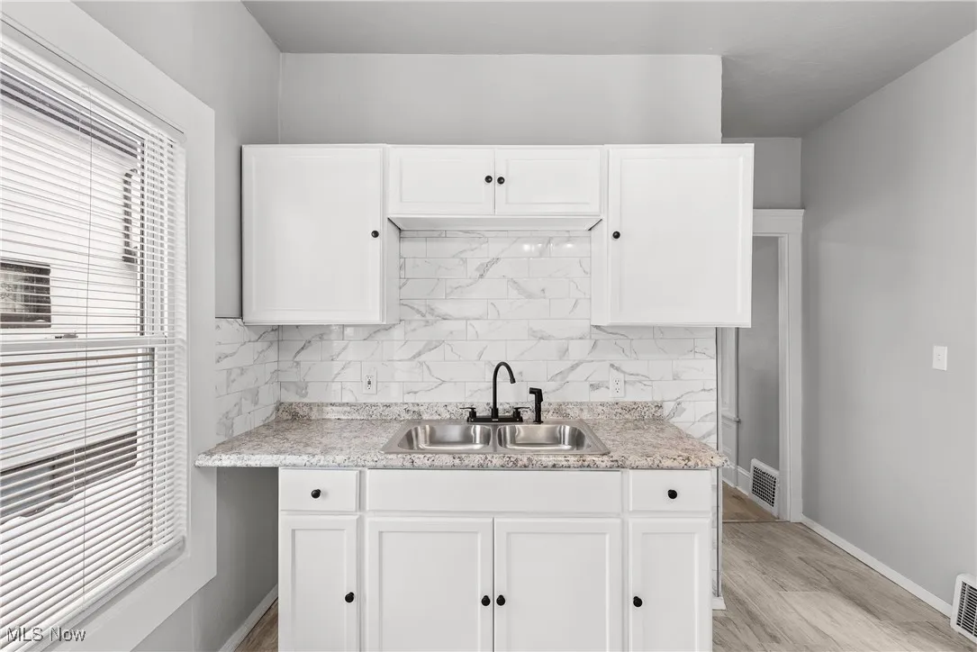 Kitchen featuring sink, white cabinets, and decorative backsplash