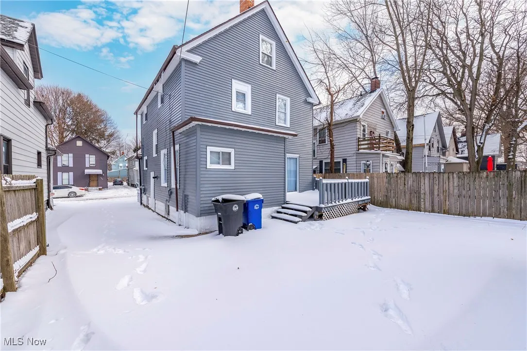 Snow covered back of property with a wooden deck