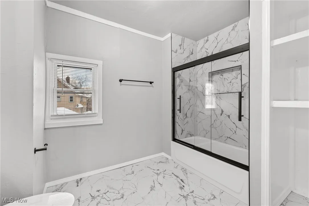Bathroom with enclosed tub / shower combo and crown molding