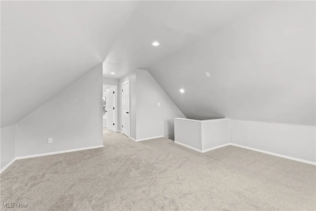 Bonus room featuring light carpet and vaulted ceiling