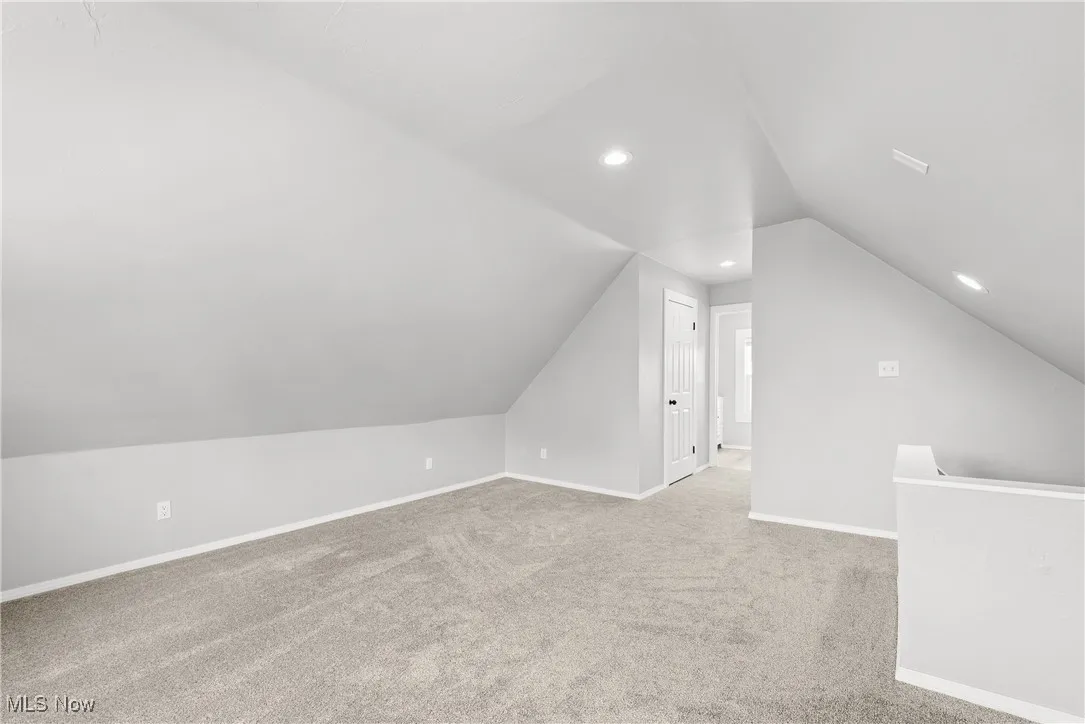 Additional living space featuring light carpet and lofted ceiling