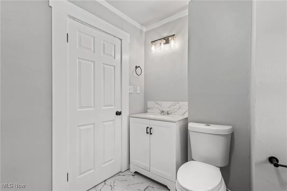 Bathroom with ornamental molding, vanity, and toilet